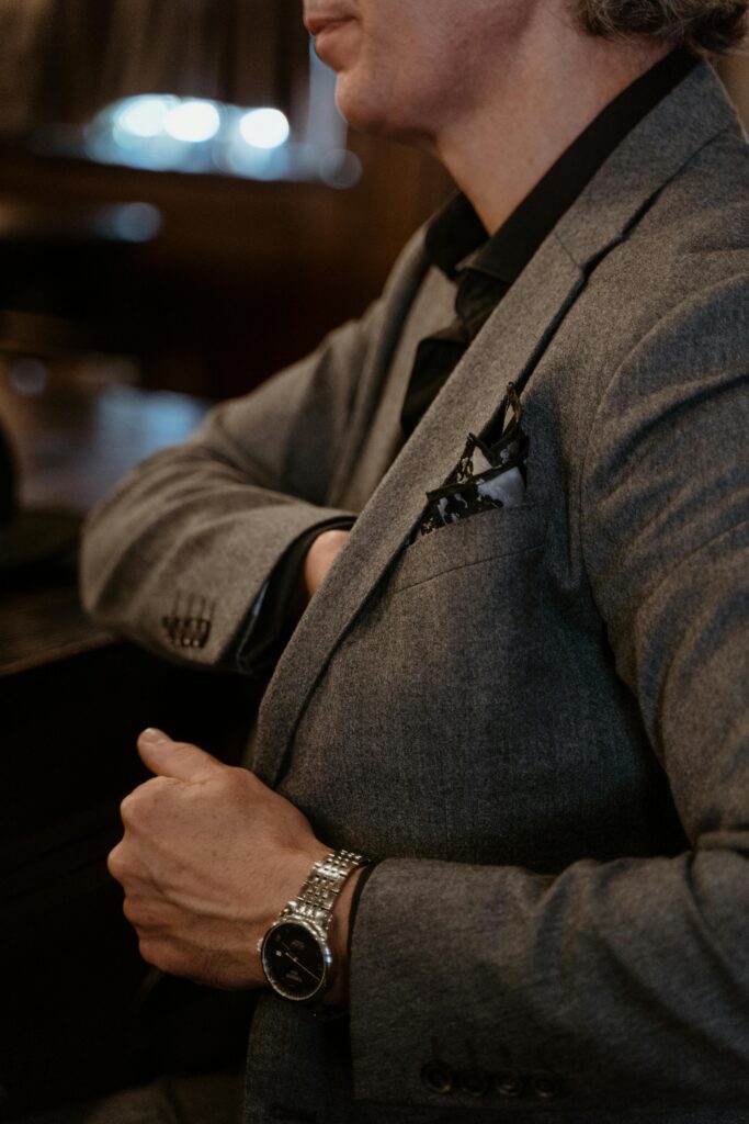 Close-up of a stylish man in a gray suit with a luxury watch, emphasizing elegance and sophistication.